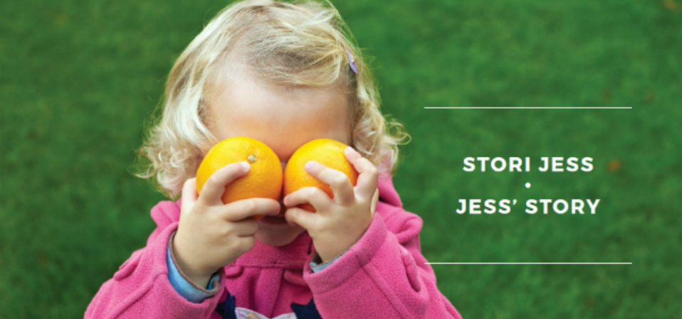 A toddler playfully holding up two oranges to her eyes