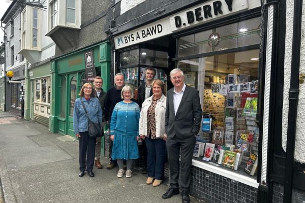 Grŵp o bobl yn sefyll y tu allan i Bys a Bawd Pawb.